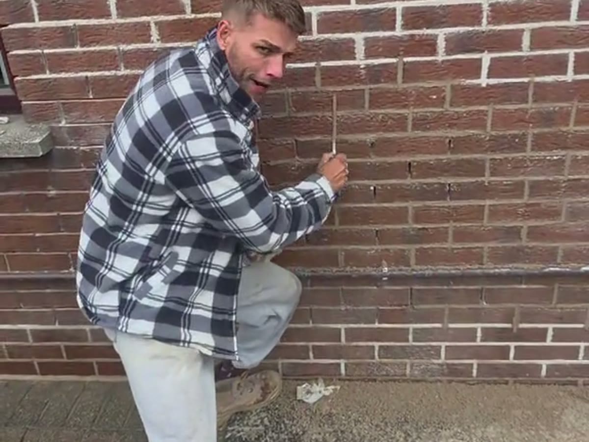 Brendan working fresh mortar into a raked out brick joint