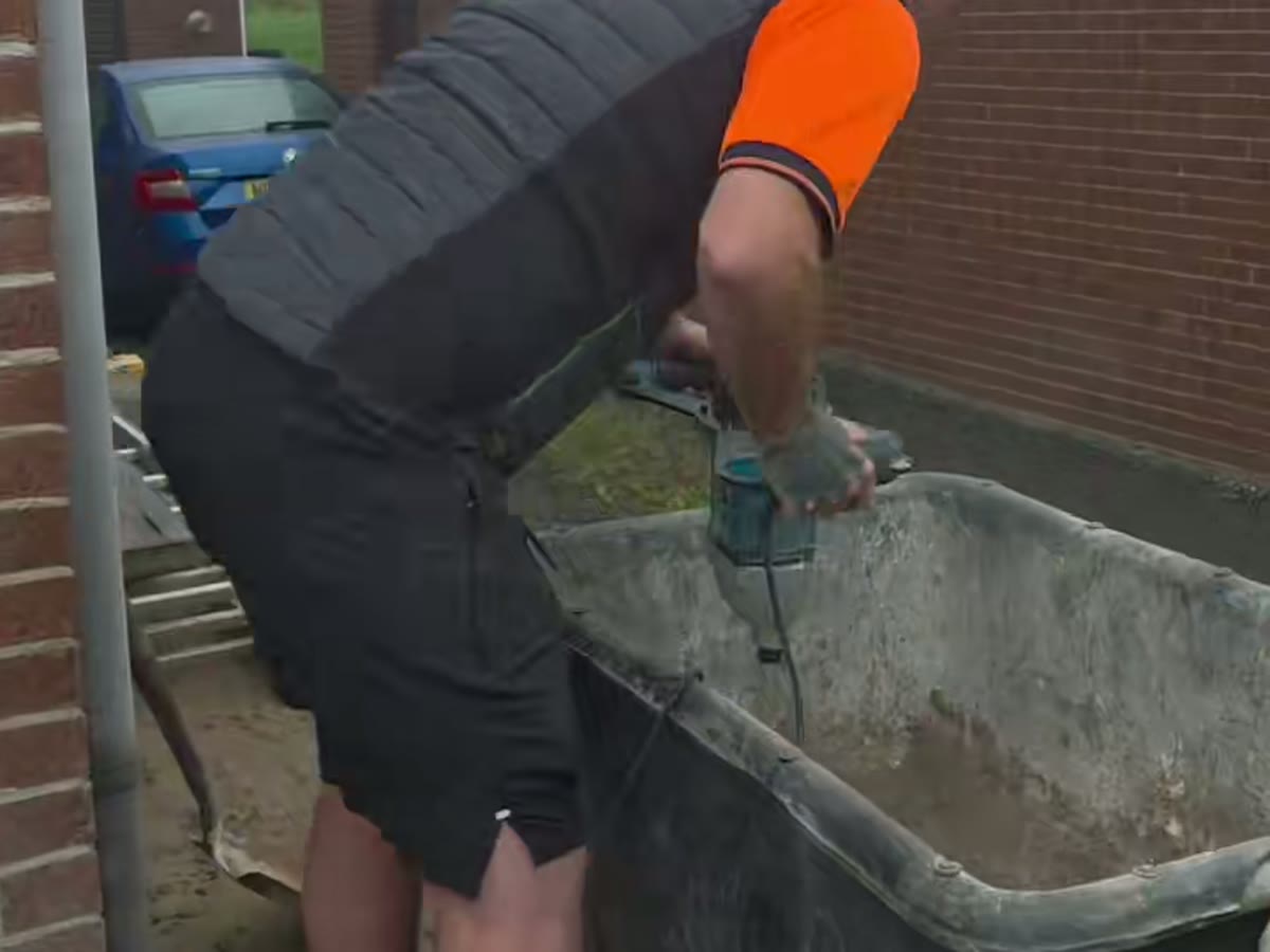 Crew member in the orange Abbey Repointing uniform mixing mortar on site